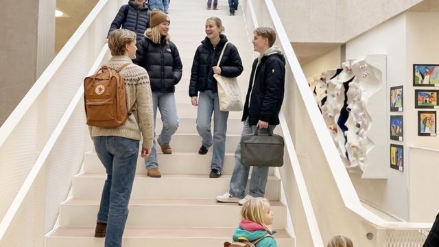 Moderne indendørs læringsmiljø på NGG i Hørsholm med dagslys, atrium og cirkelformede lamper.