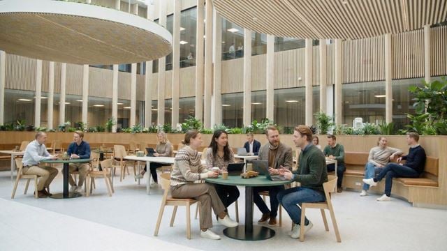 Moderne indendørs atrium med træsøjler og grønne planter i multibrugerhuset på Ejby Industrivej.