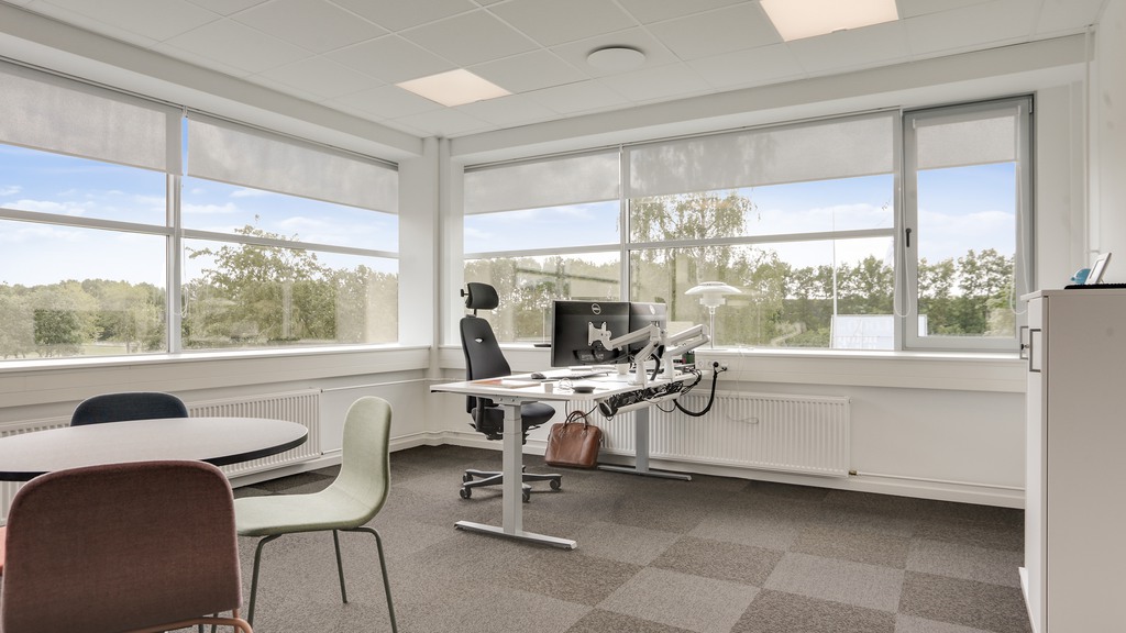 Lyst og moderne kontorlokale med store vinduer og udsigt til grønne områder i Ballerup.