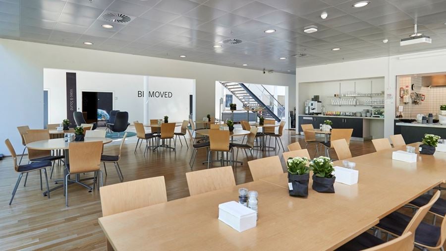 Moderne lys kantine med træborde og stole i erhvervsejendommen Industriparken 29 i Ballerup.