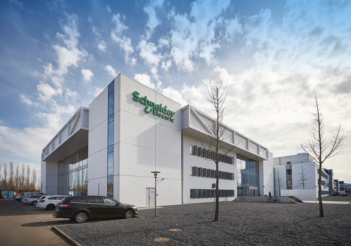 Moderne erhvervsejendom på Lautrupvang 1 i Ballerup med Schneider Electric logo og parkeringspladser.