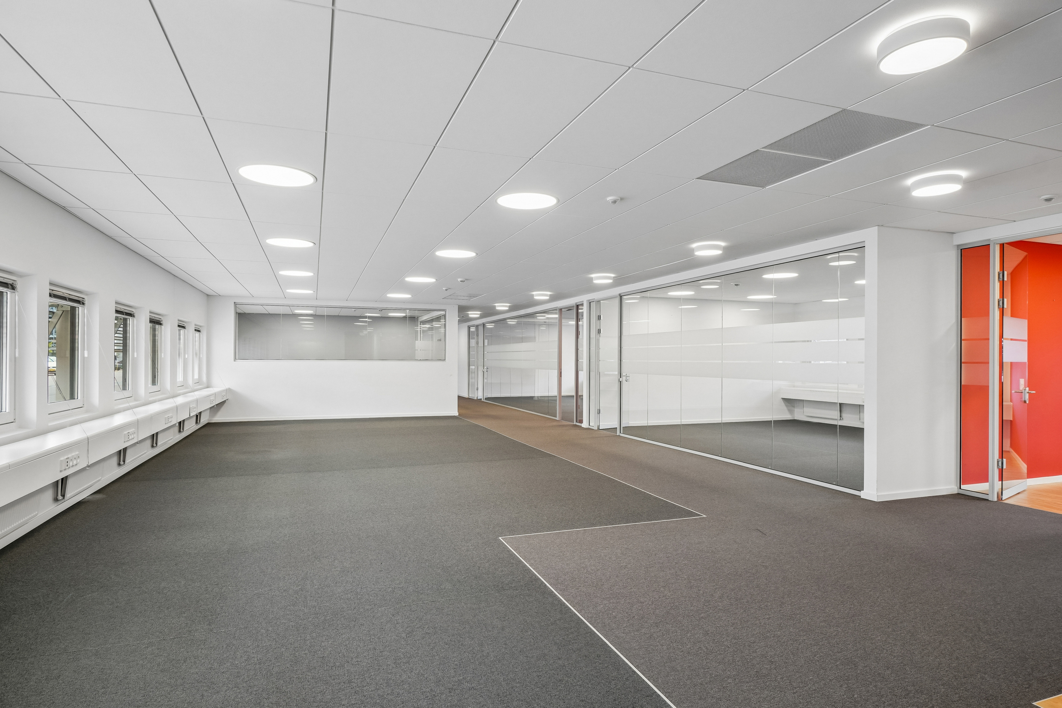 Lyst og moderne kontorlokale med glasvægge og mørke tæpper på Borupvang i Ballerup.